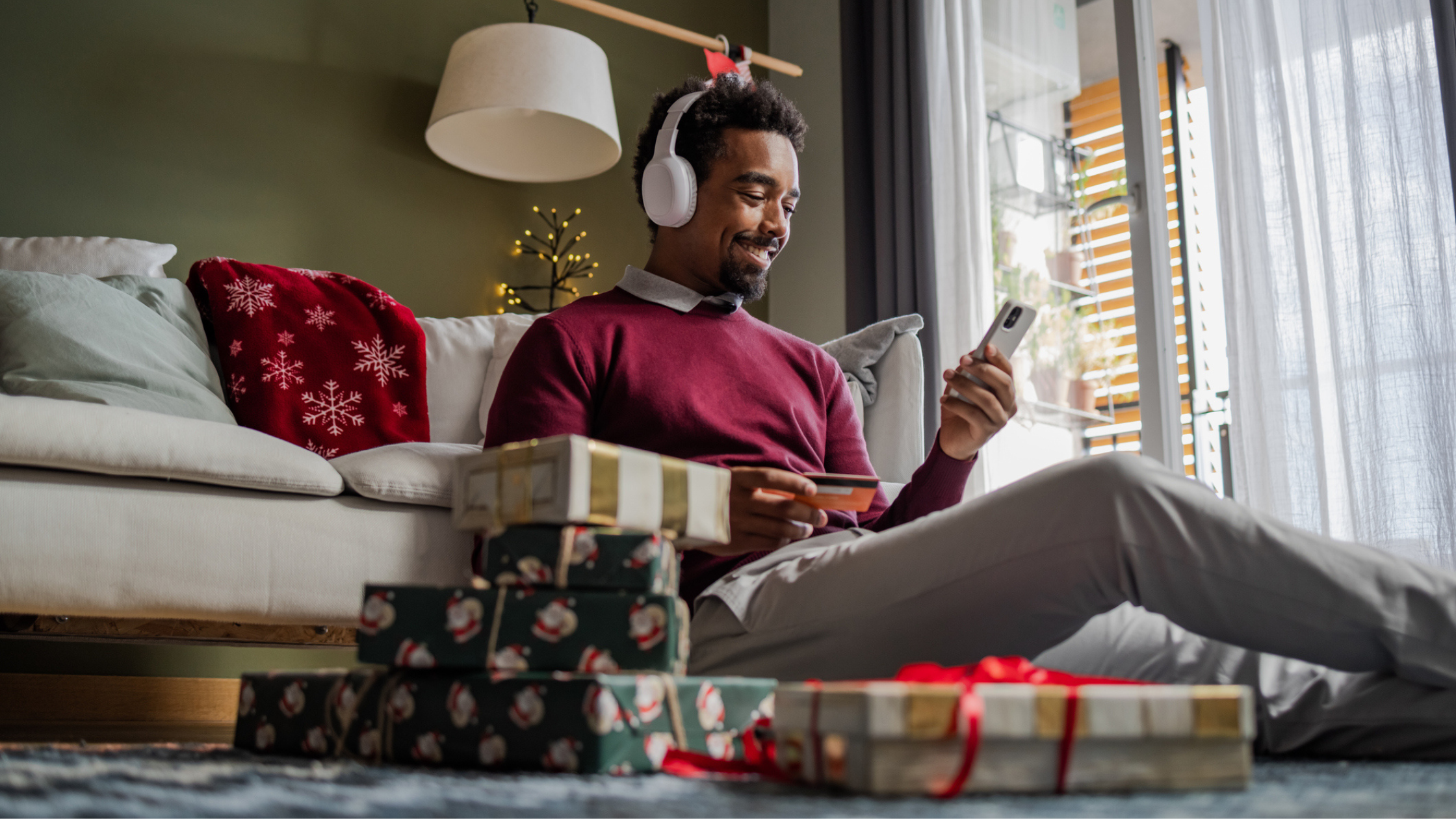 Man listening to ear phones and doing holiday shopping on his phone